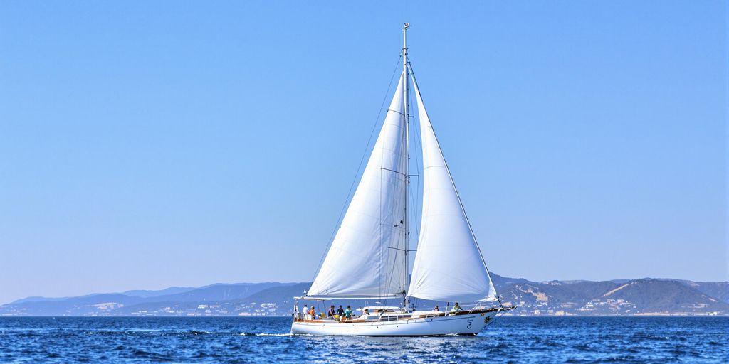 Klassisches Segelboot auf ruhiger See unter blauem Himmel.